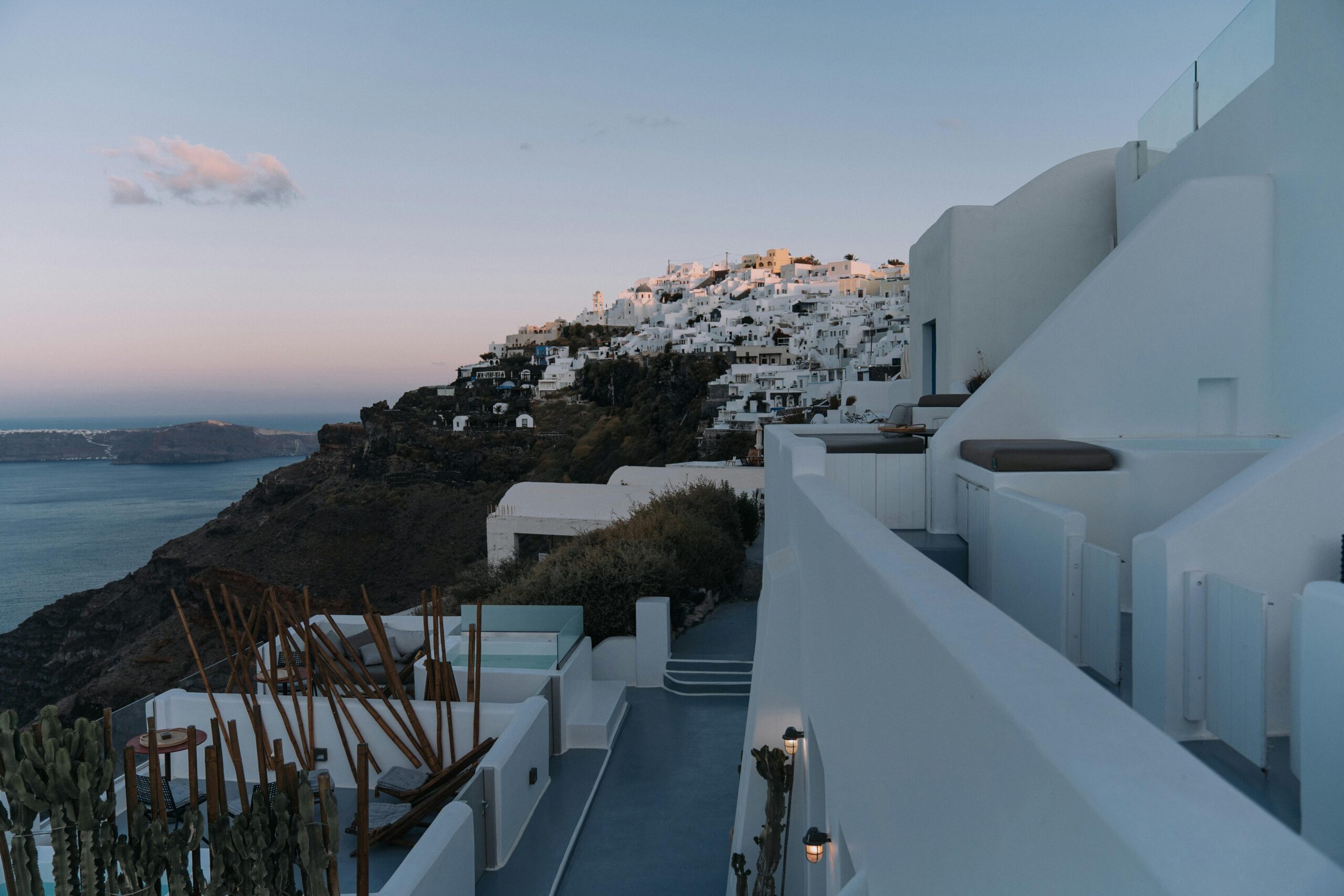 An enchanting view of Santorini's iconic white buildings on a cliff overlooking the Aegean Sea at dawn.